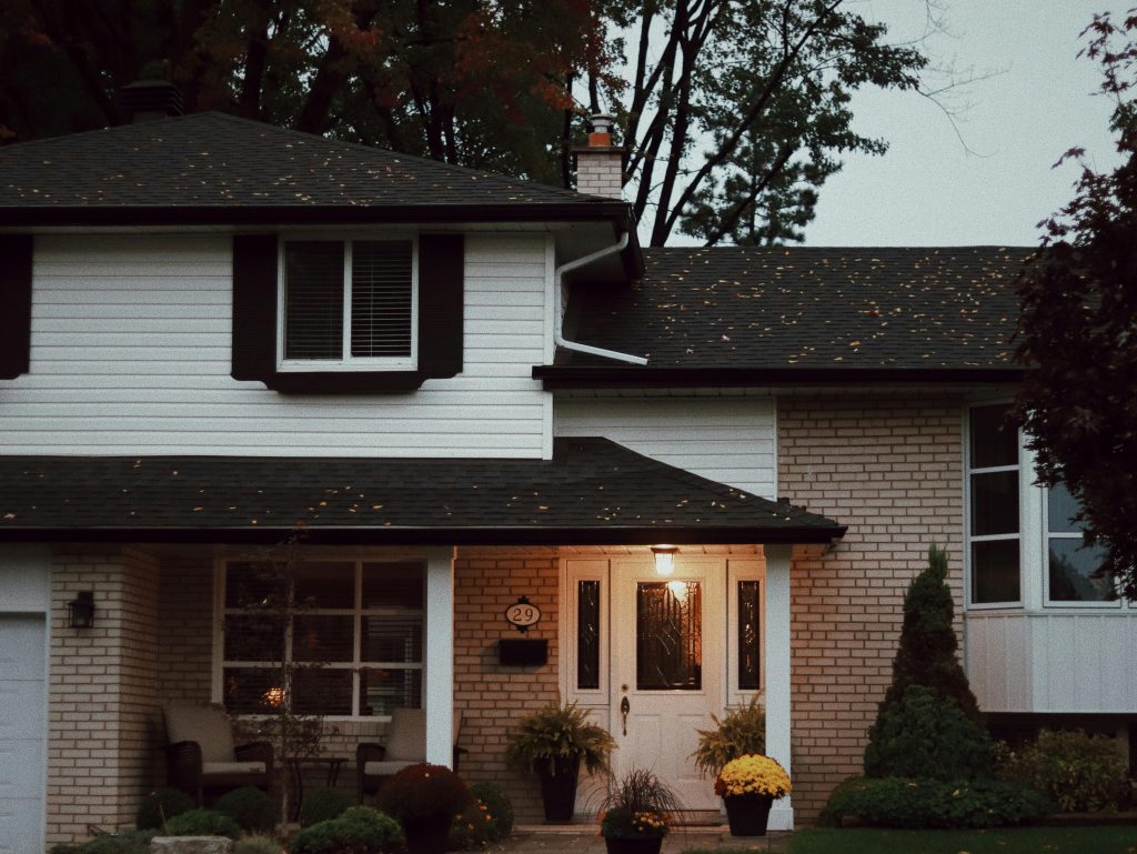 pexels photo 17131036 17131036 A cozy suburban house with a welcoming porch and lush potted plants at dusk.